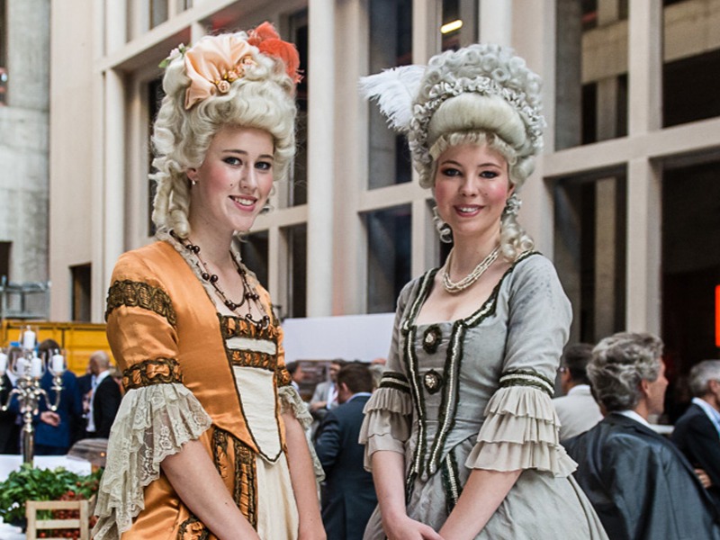 Zwei Hostessen in edler Kleidung mit Perücken im Stil des 18. Jahrhunderts, lächeln in die Kamera bei historischer Event und Promotion Inszenierung