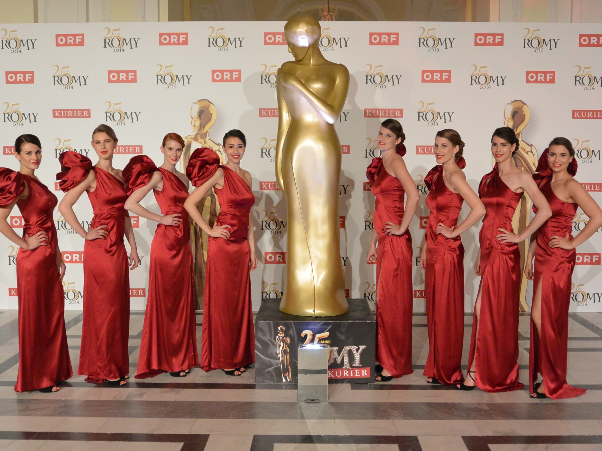 Hostessen in roten Abendkleidern neben einer Statue, elegante Inszenierung bei Event, Gala und stilvoller Markenpräsentation