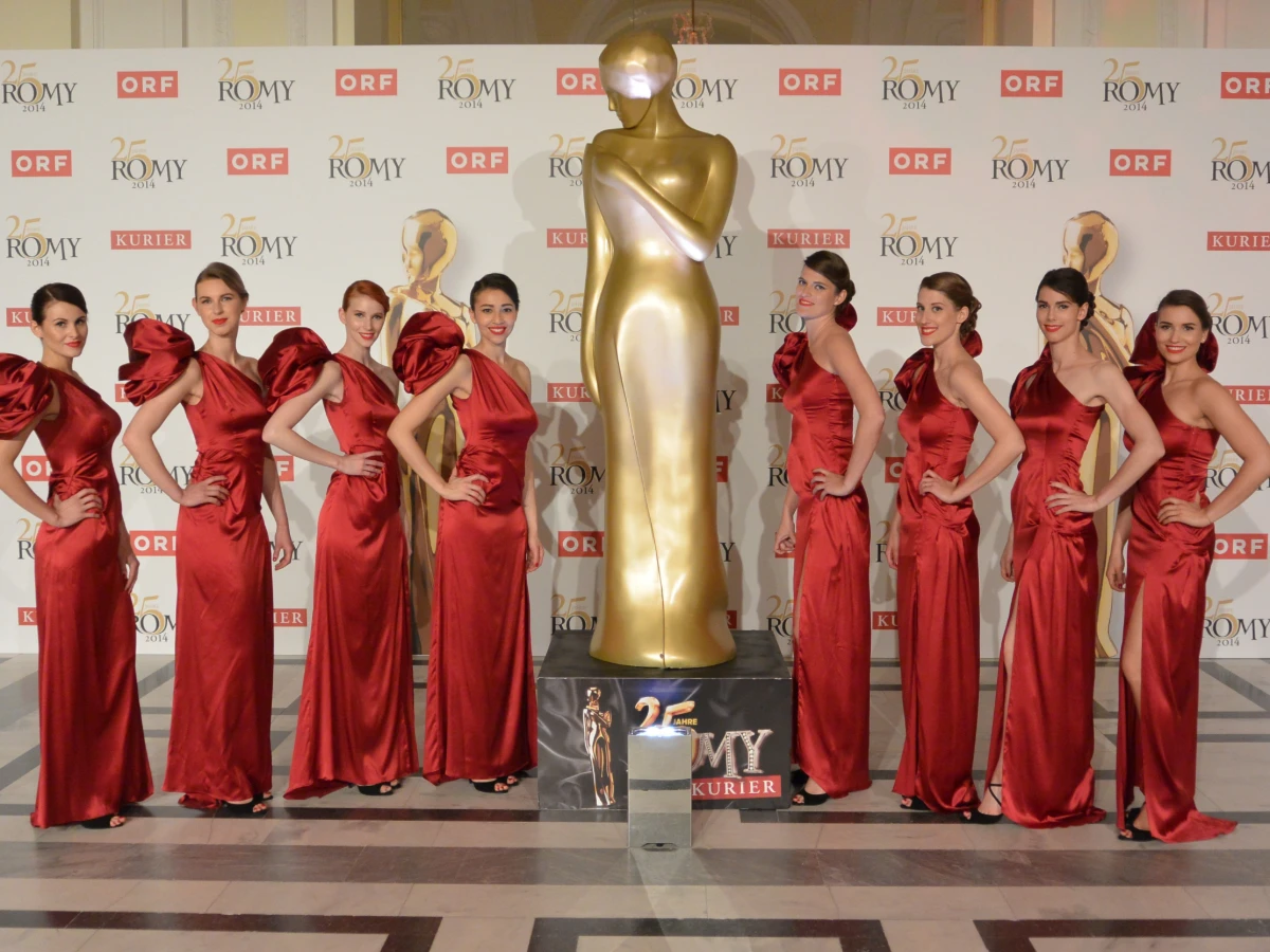 Hostessen in roten Abendkleidern neben einer Statue, elegante Inszenierung bei Event, Gala und stilvoller Markenpräsentation