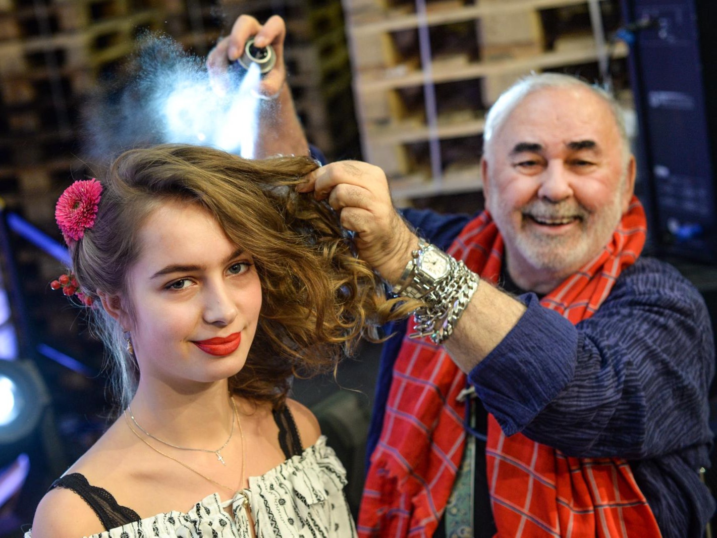 Lächelnde Hostess beim Styling, Visagist sprüht Haarspray ins Haar, professionelle Vorbereitung für Event, Shooting und Promotion