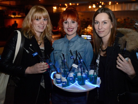 Freundliche Hostess mit Tablet und Wasserflaschen im Gespräch mit zwei Gästen, professioneller Service und Betreuung bei Event und Veranstaltung