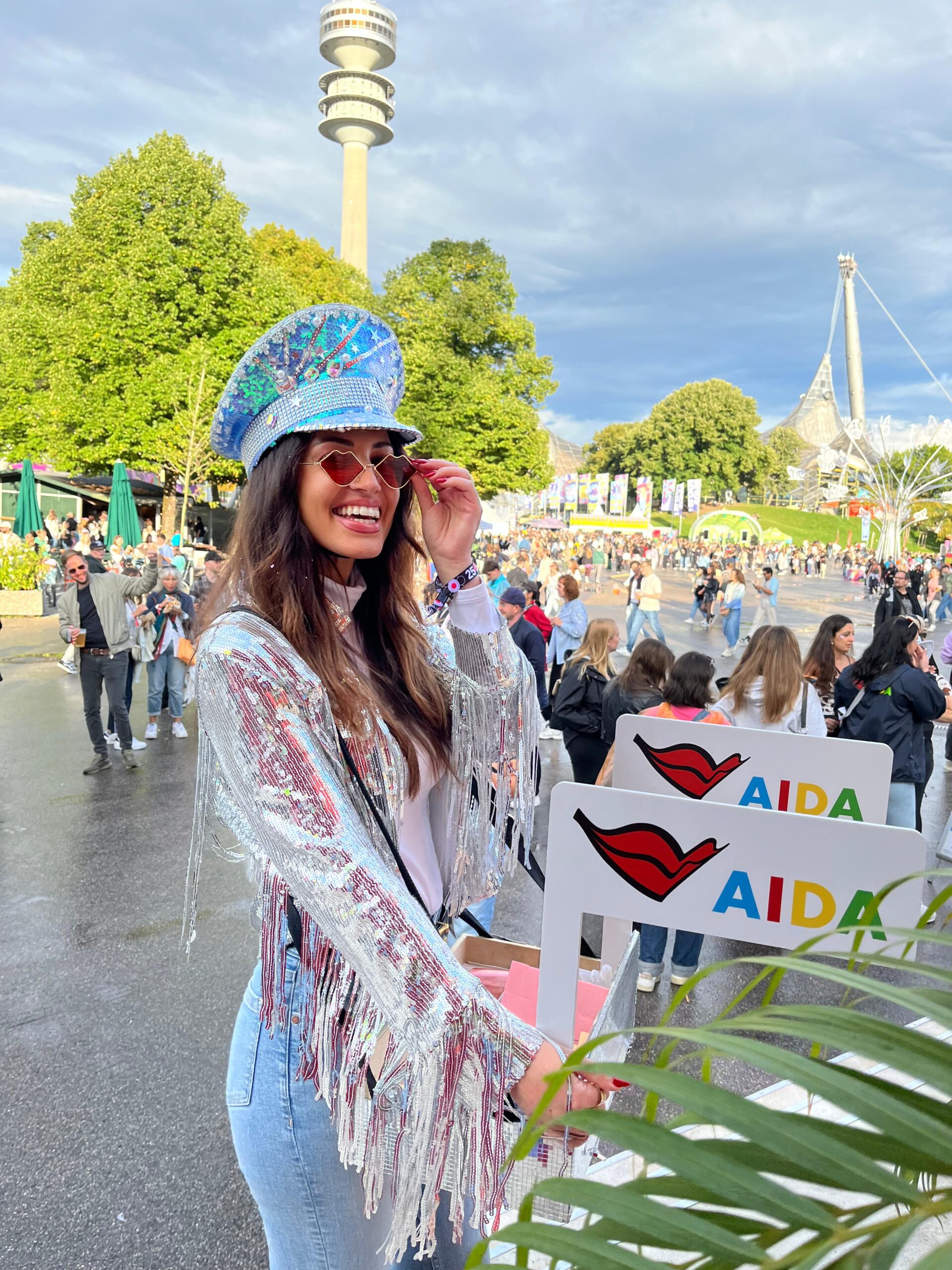 Promotion Hostess mit Bauchladen im Glitzer-Outfit läuft über ein Festival, lächelnder Einsatz bei AIDA Promotion und Markenaktivierung