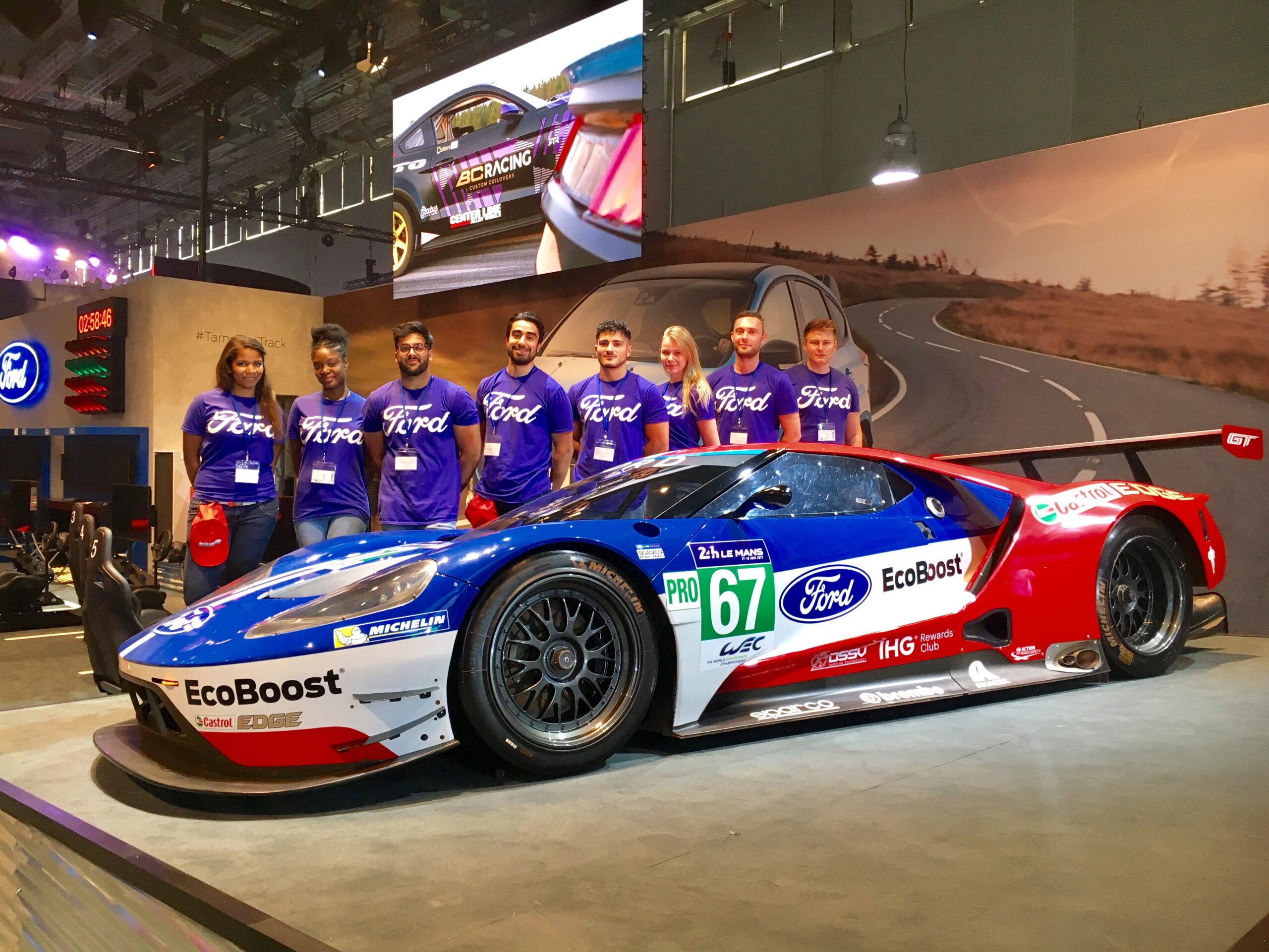 Ford Rennauto mit acht Personen in Ford T-Shirts dahinter, Promotion Team bei Motorsport Event und Markenpräsentation im Einsatz