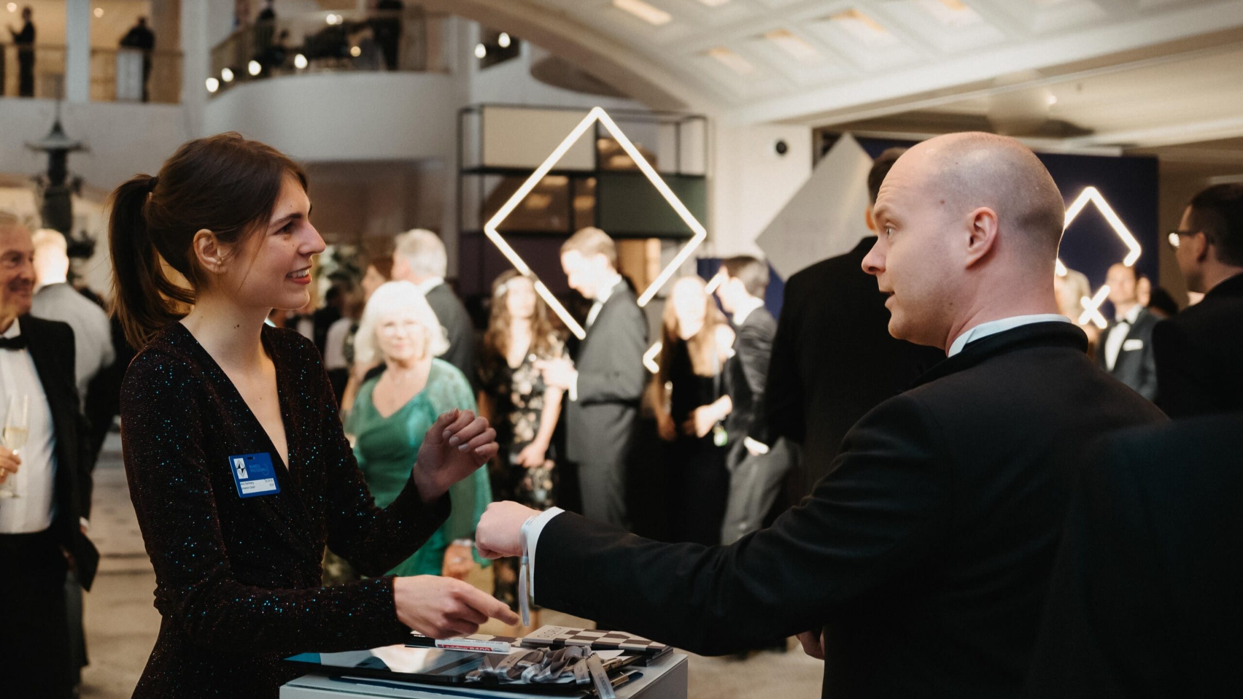 Hostess legt einem Gast ein Einlassband am Handgelenk an, professioneller Check-in Service bei Event, Messe und Veranstaltung