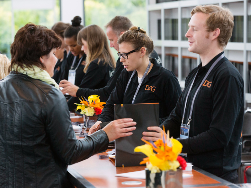 Host und Hostess stehen hinter einem Tresen bei einem Kongress, Akkreditierung und Check-in für Gäste bei Event und Konferenz