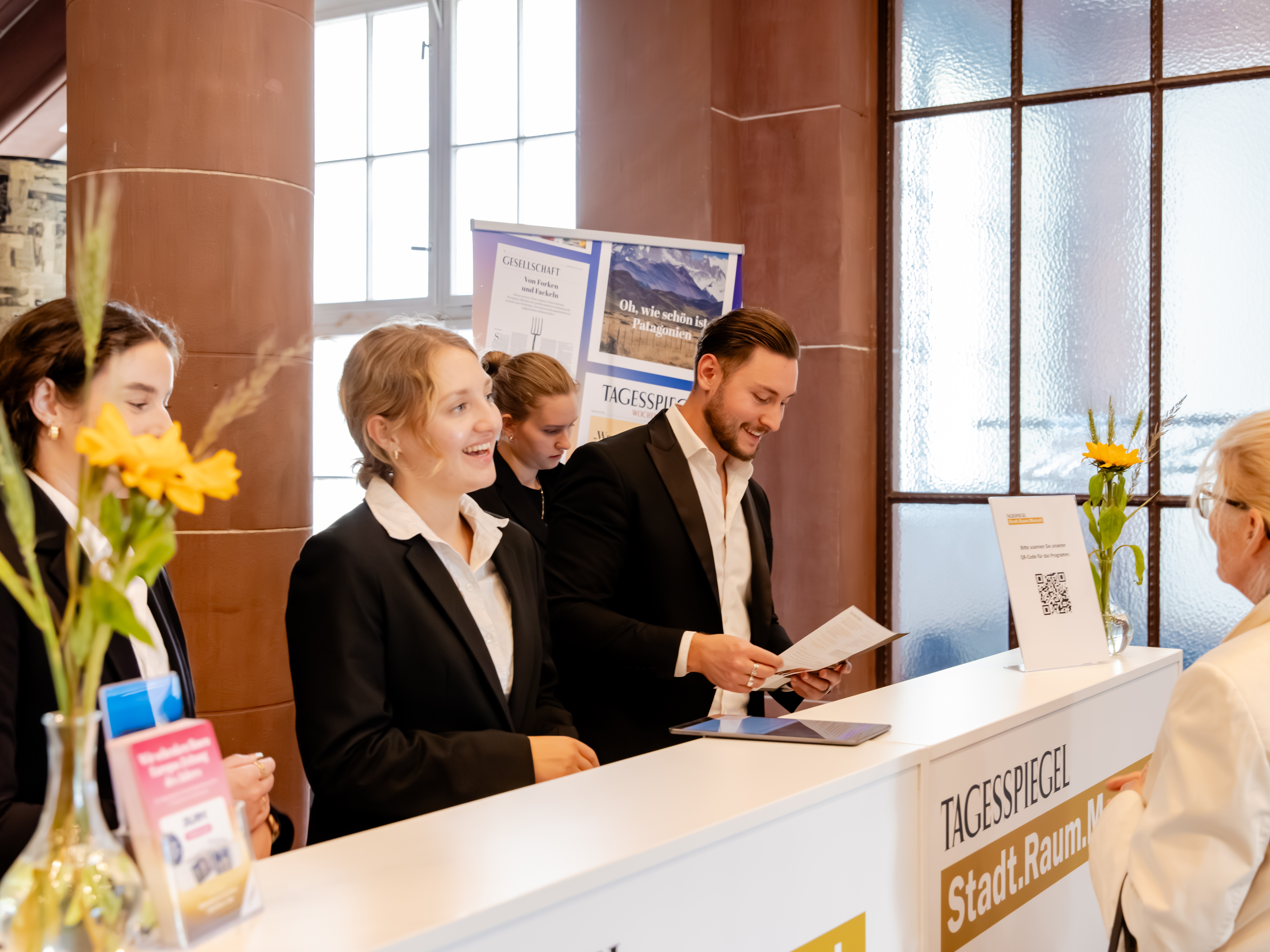 Hostessen im eleganten Hosenanzug mit weißem Hemd an der Akkreditierung, lächelnder Empfang und professionelle Gästebetreuung bei Event und Messe