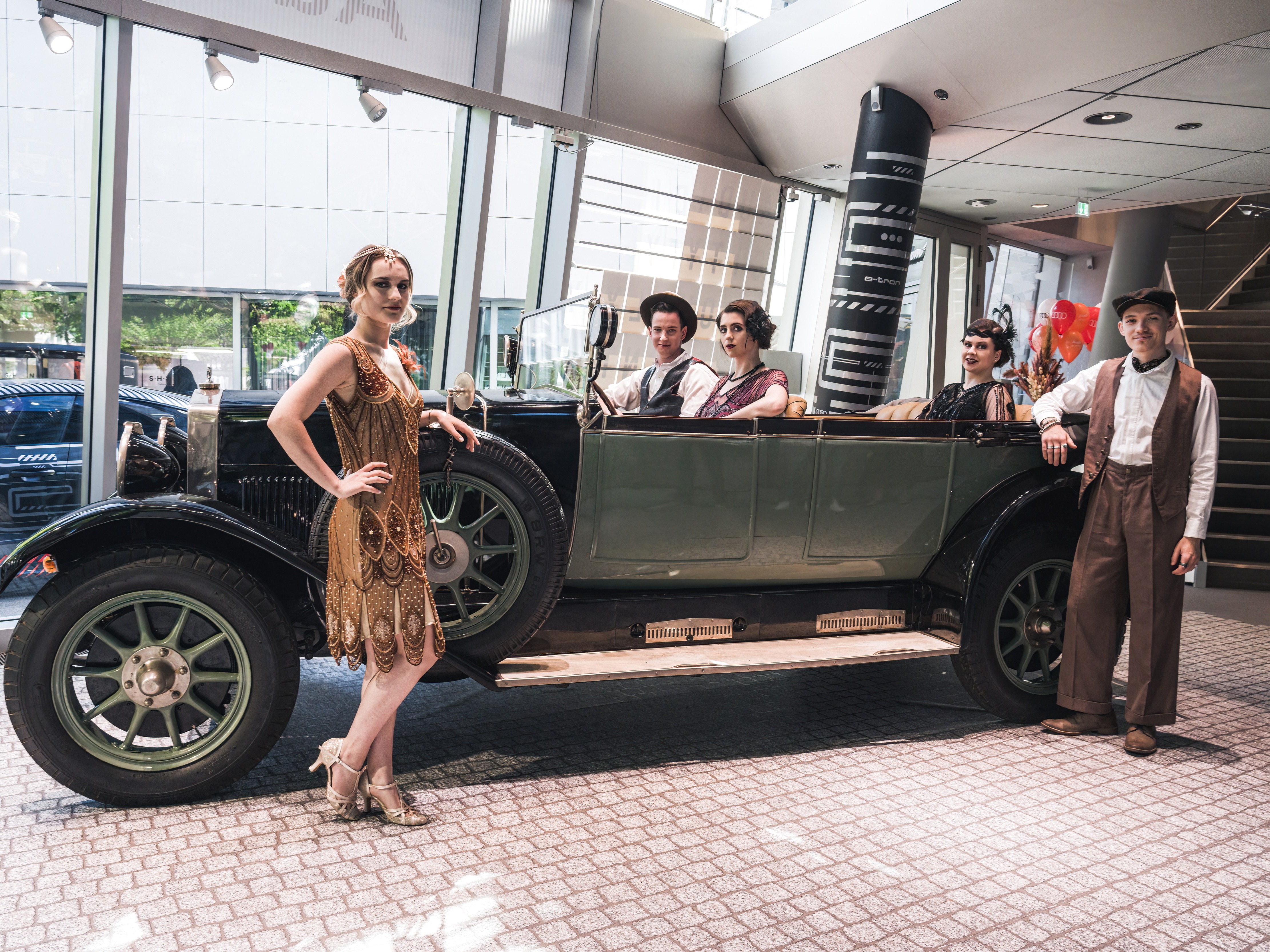 Hosts und Hostessen im Stil der 60er Jahre in und vor einem Oldtimer bei einem Fotoshooting, elegante Inszenierung für Event, Promotion und Markenauftritt