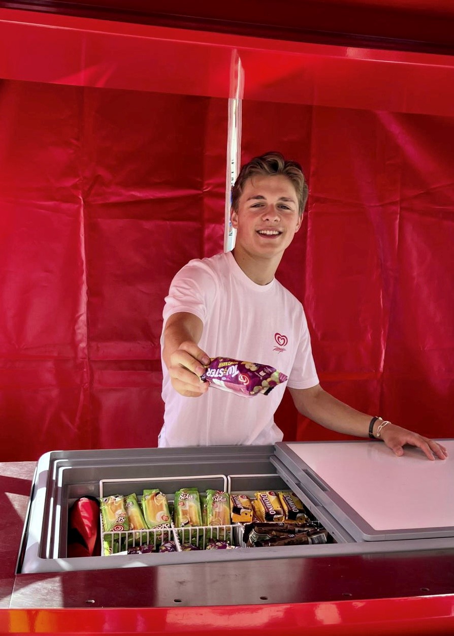 Promoter im roten Oberteil verteilt Eis in einem roten Zelt, Sampling Aktion bei Event, Festival und sommerlicher Markenpromotion