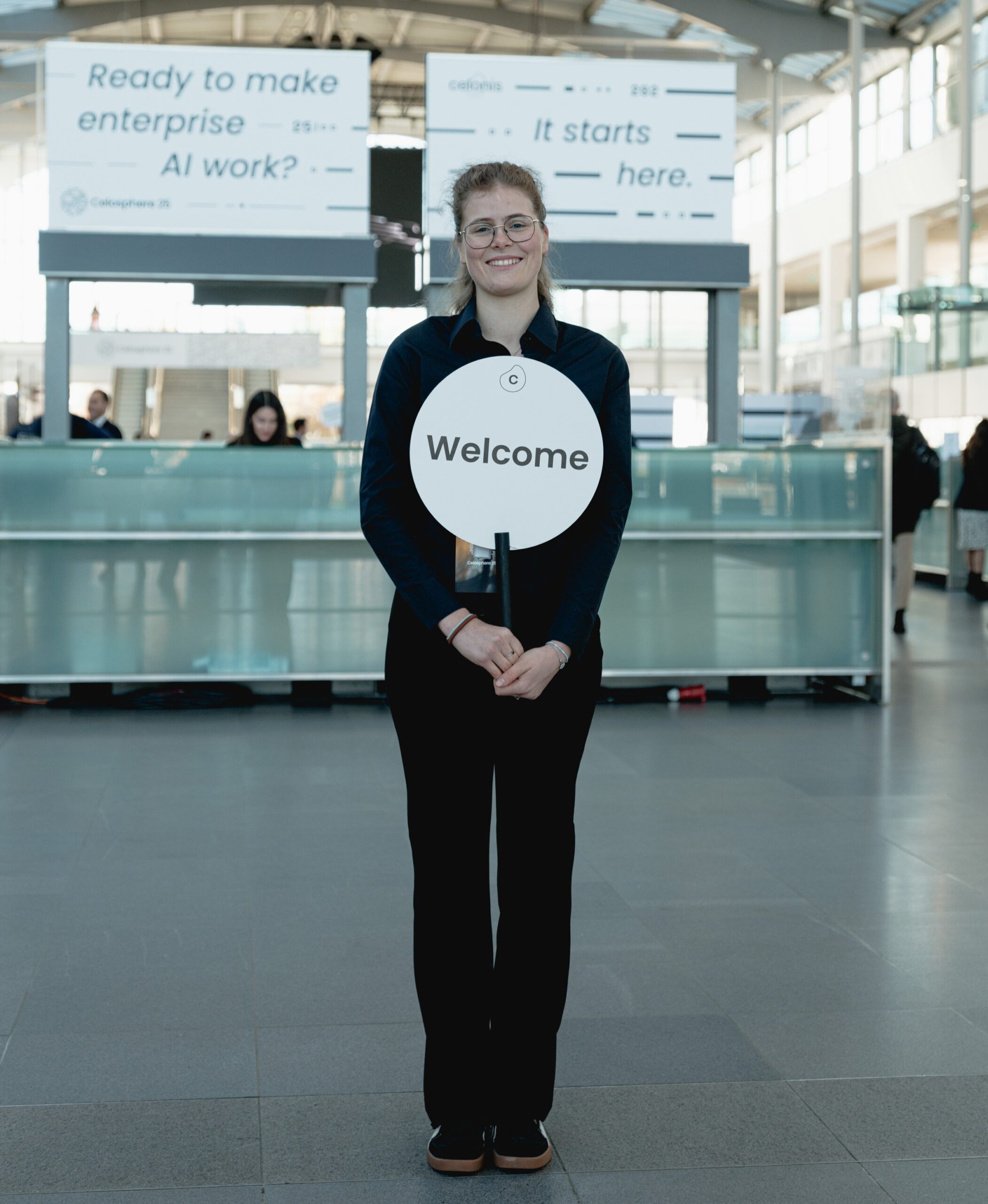 Transferhostess im schwarzen Outfit bereit zur Begrüßung von Gästen, freundlicher Empfangsservice bei Event, Messe und Veranstaltung