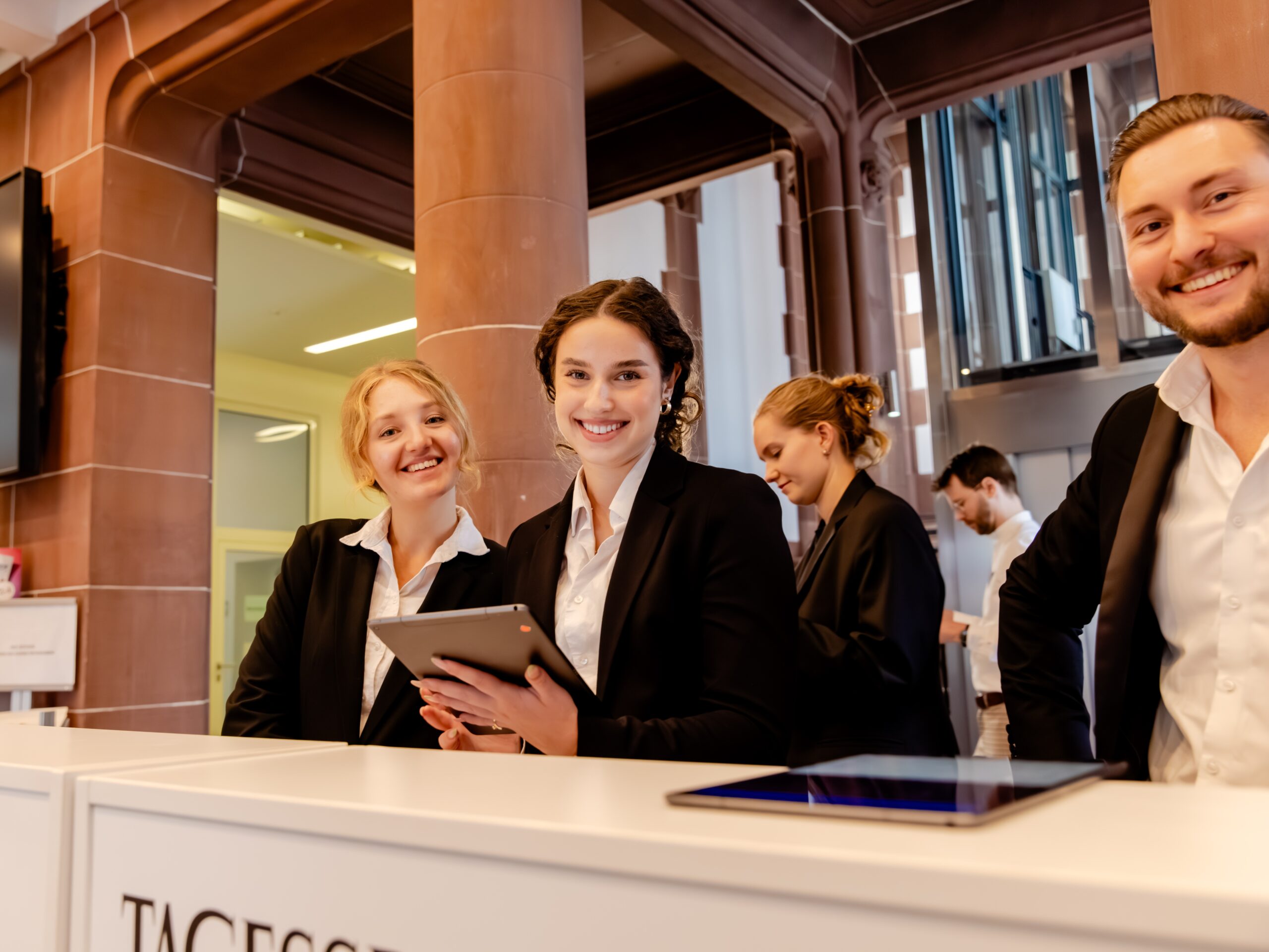 Hostessen im schwarzen Hosenanzug mit weißem Hemd arbeiten an der Akkreditierung, lächelnder und professioneller Empfang bei Event und Messe