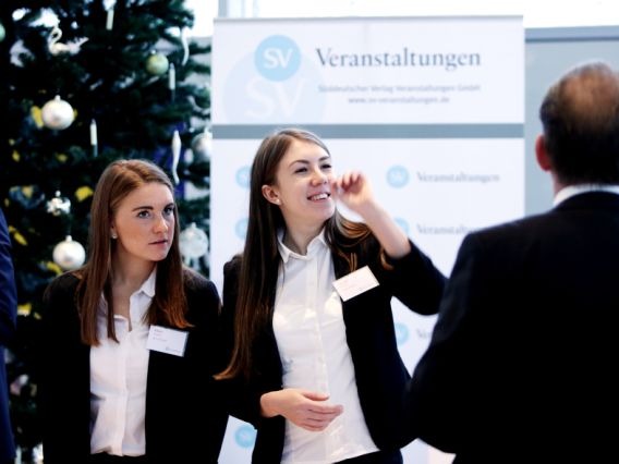 Zwei Hostessen im Hosenanzug an der Akkreditierung, kümmern sich um Check-in und Wohlbefinden der Gäste bei Event und Messe
