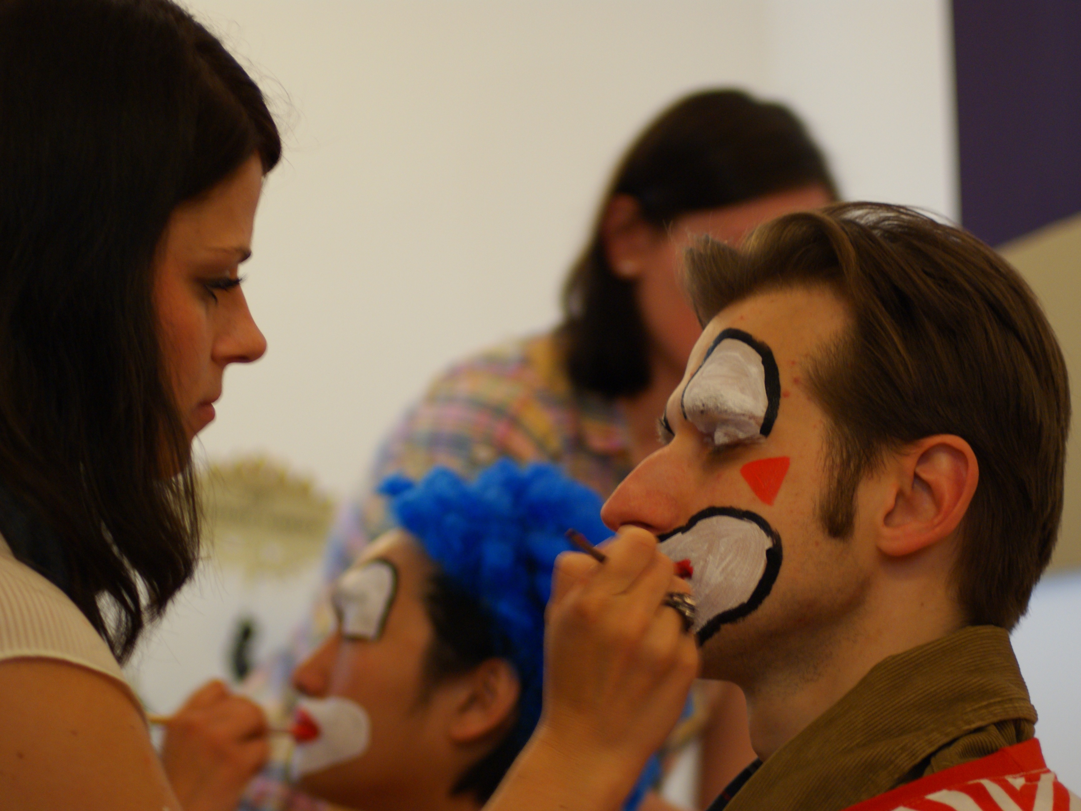 Visagistin schminkt einen Mann zum Clown, professionelle Vorbereitung für Promotion, Event und Entertainment Einsatz