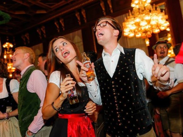 Zwei Personen im Bierzelt mit Getränken in der Hand in traditioneller deutscher Kleidung, Oktoberfest Atmosphäre bei Event und Promotion Einsatz