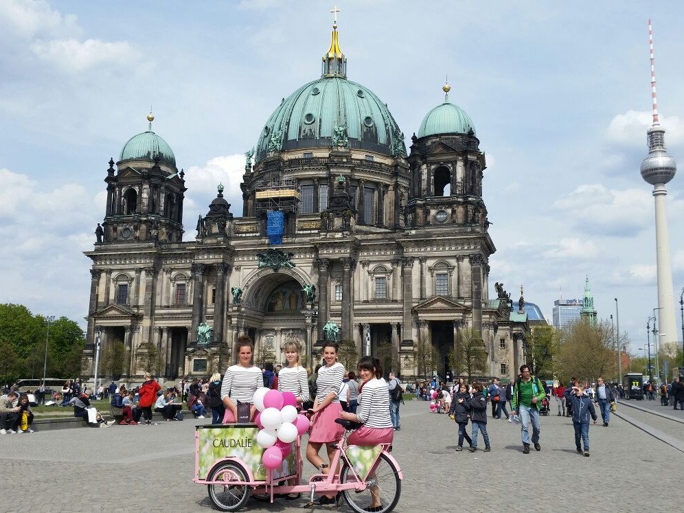Vier Hostessen vor dem Pergamonmuseum auf der Museumsinsel in Berlin, einheitlich gekleidet in weißen Oberteilen und pinken Röcken bei Promotion Event