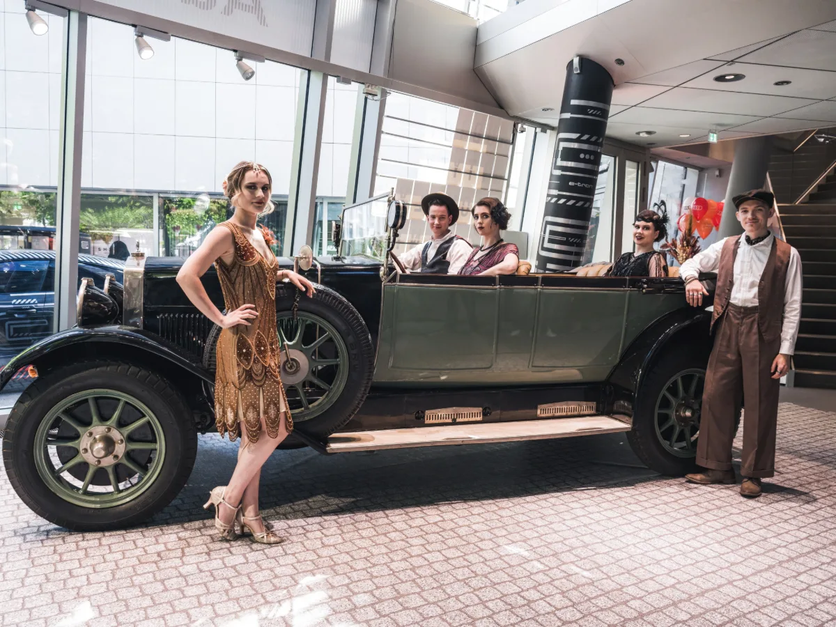 Hosts und Hostessen im Stil der 60er Jahre in und vor einem Oldtimer bei einem Fotoshooting, elegante Inszenierung für Event, Promotion und Markenauftritt