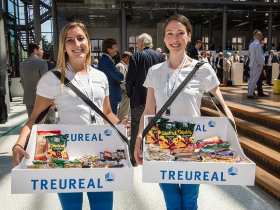Zwei Promotion Hostessen in weißen T-Shirts und Jeans verteilen Produkte aus Bauchläden, lächelnder Sampling Einsatz bei Event und Markenaktion