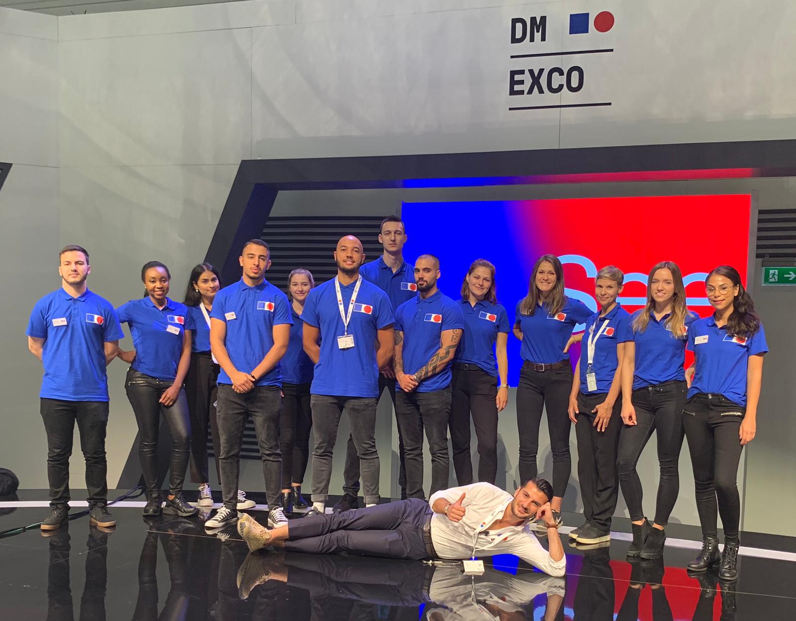 Messe-Team aus Host und Hostessen in einheitlichen Outfits vor einem Messestand, professioneller Auftritt bei Promotion, Event und Markenpräsentation
