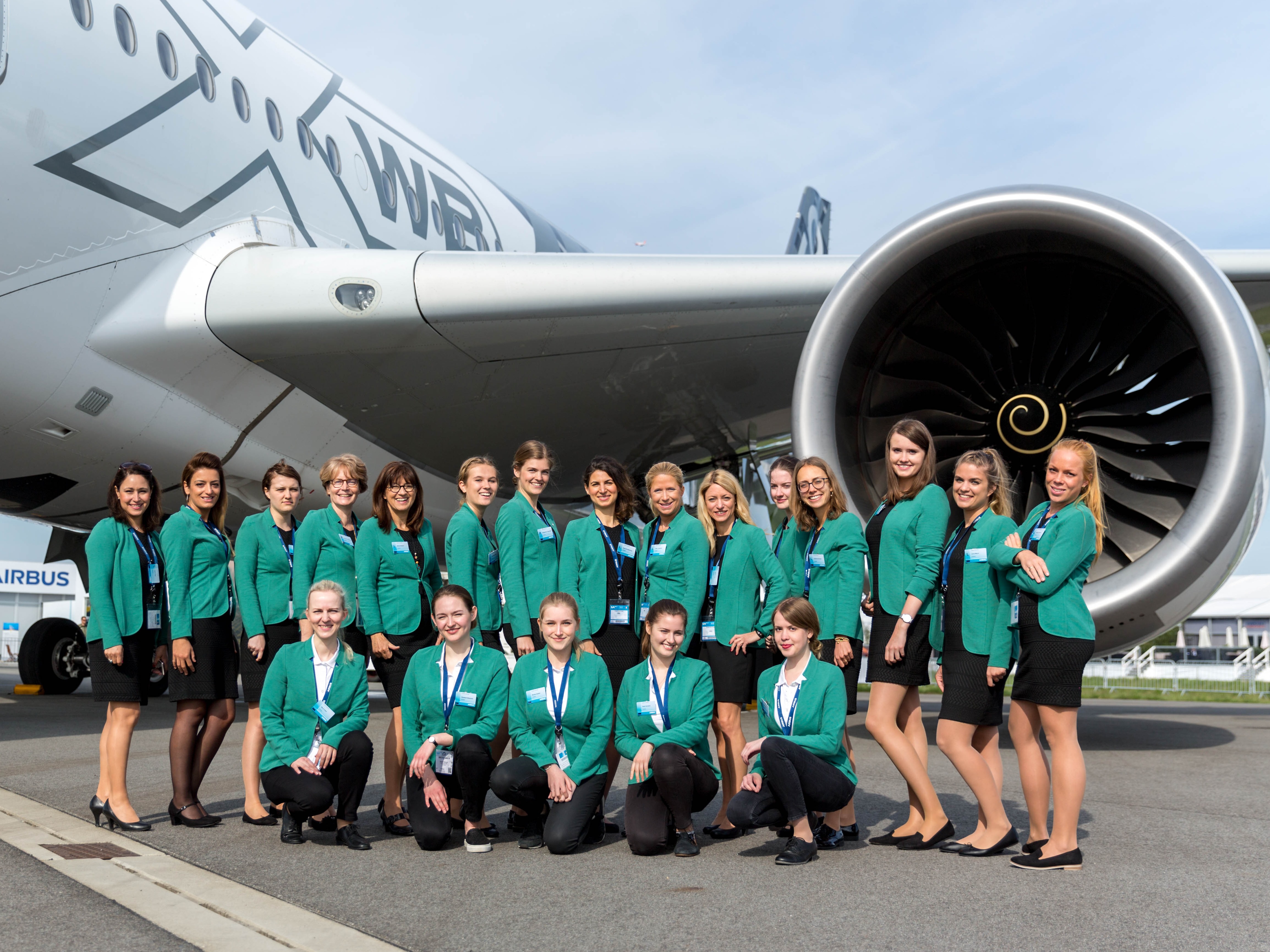 Mehrere Personen in gr&uuml;nen Outfits stehen vor einem Flugzeug, Promotion Team im Einsatz bei Event, Messe und Flughafenaktion