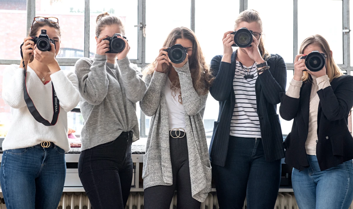 Fünf Frauen fotografieren mit Kameras in Richtung Betrachter