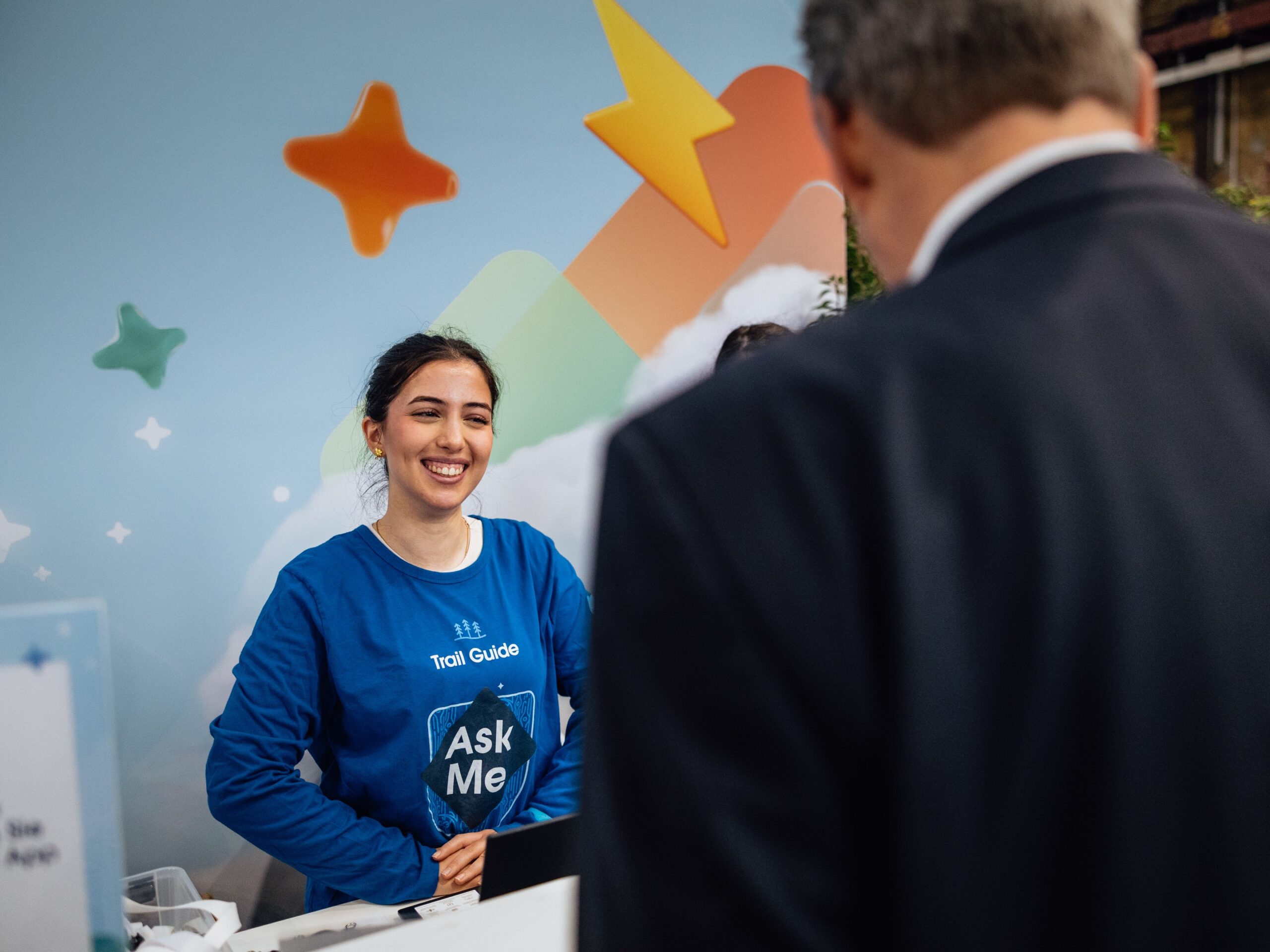 Messehostess auf der Agentforce Messe in Düsseldorf im blauen Pullover im Gespräch mit einem Gast, professioneller Empfangs- und Eventservice