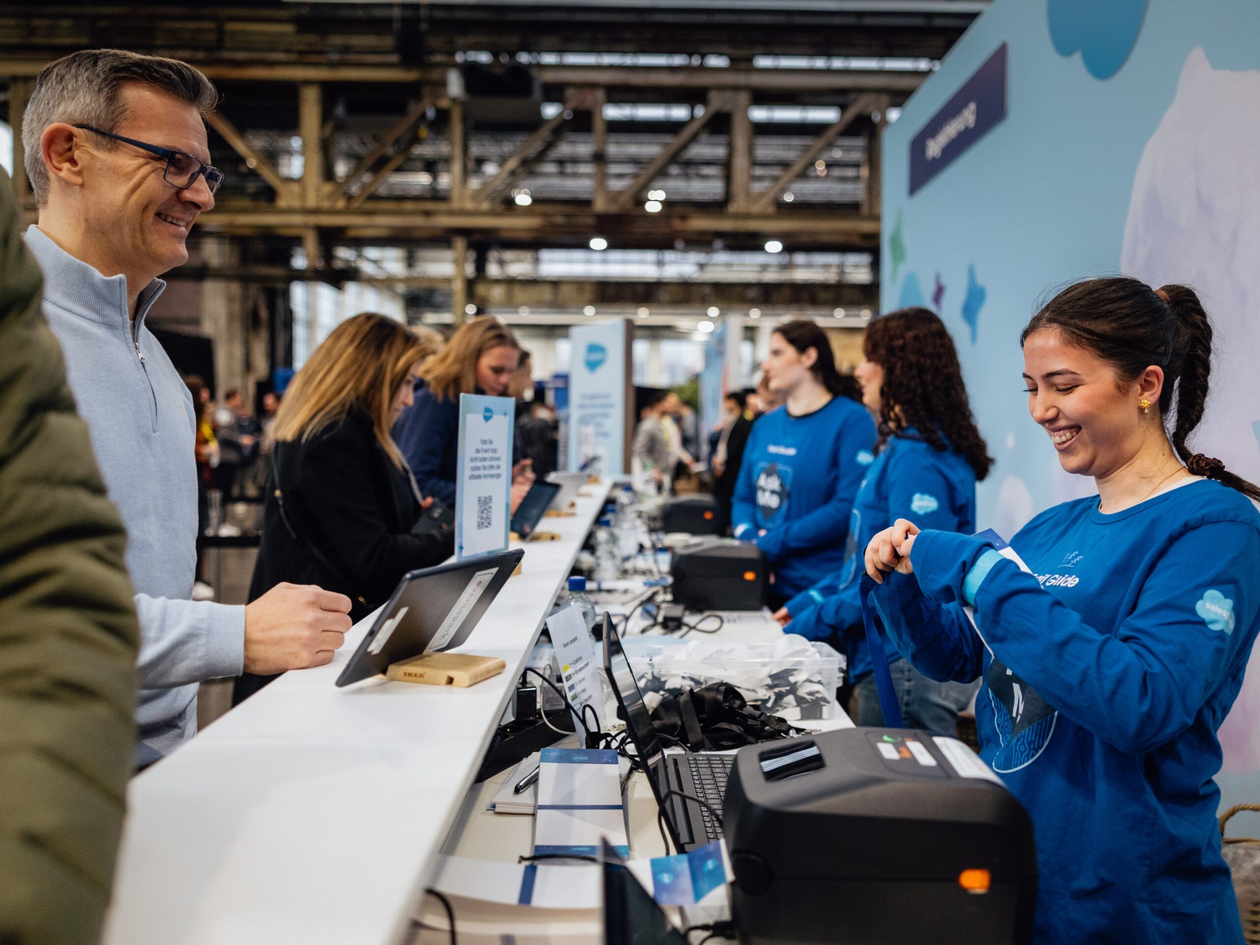 cinnamon Messehostess auf der Agentforce Messe in Düsseldorf hinter einem Stand im blauen Pullover, professioneller Empfangs- und Promotionservice bei Event und Konferenz