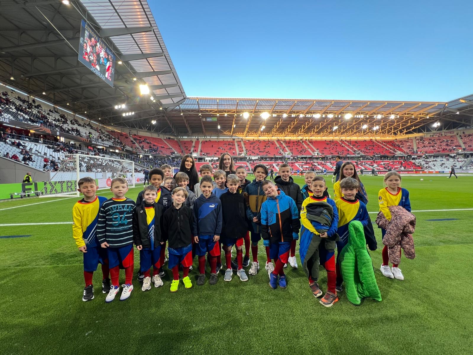 Einlaufkinder auf dem Fußballplatz mit Jacken in der Hand blicken glücklich in die Kamera, emotionale Matchday Atmosphäre bei Sportevent in Freiburg