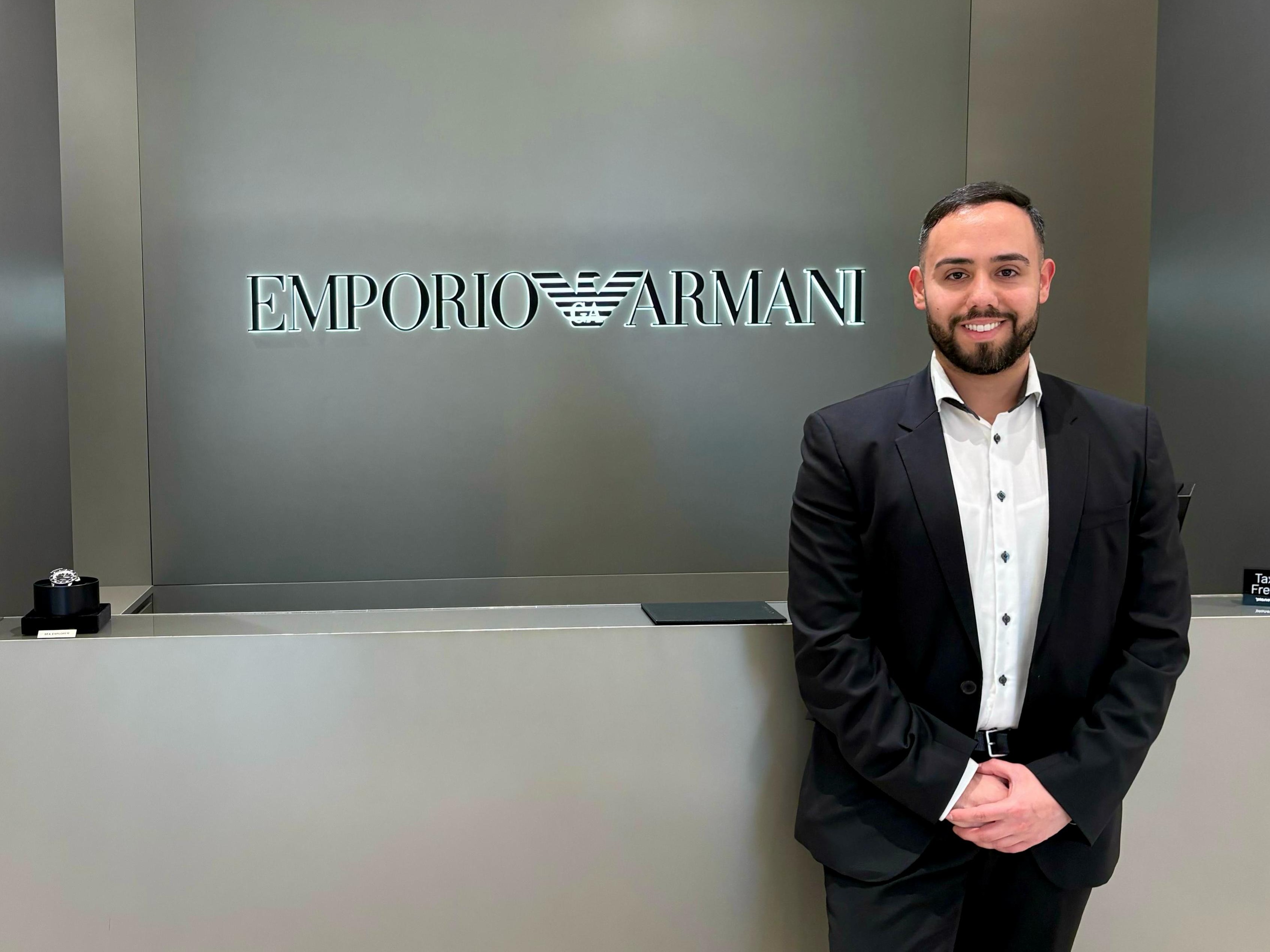 Host im Smoking vor dem Emporio Armani Logo lächelt in die Kamera, eleganter Empfangsservice bei Luxus-Event und Store Promotion in Berlin