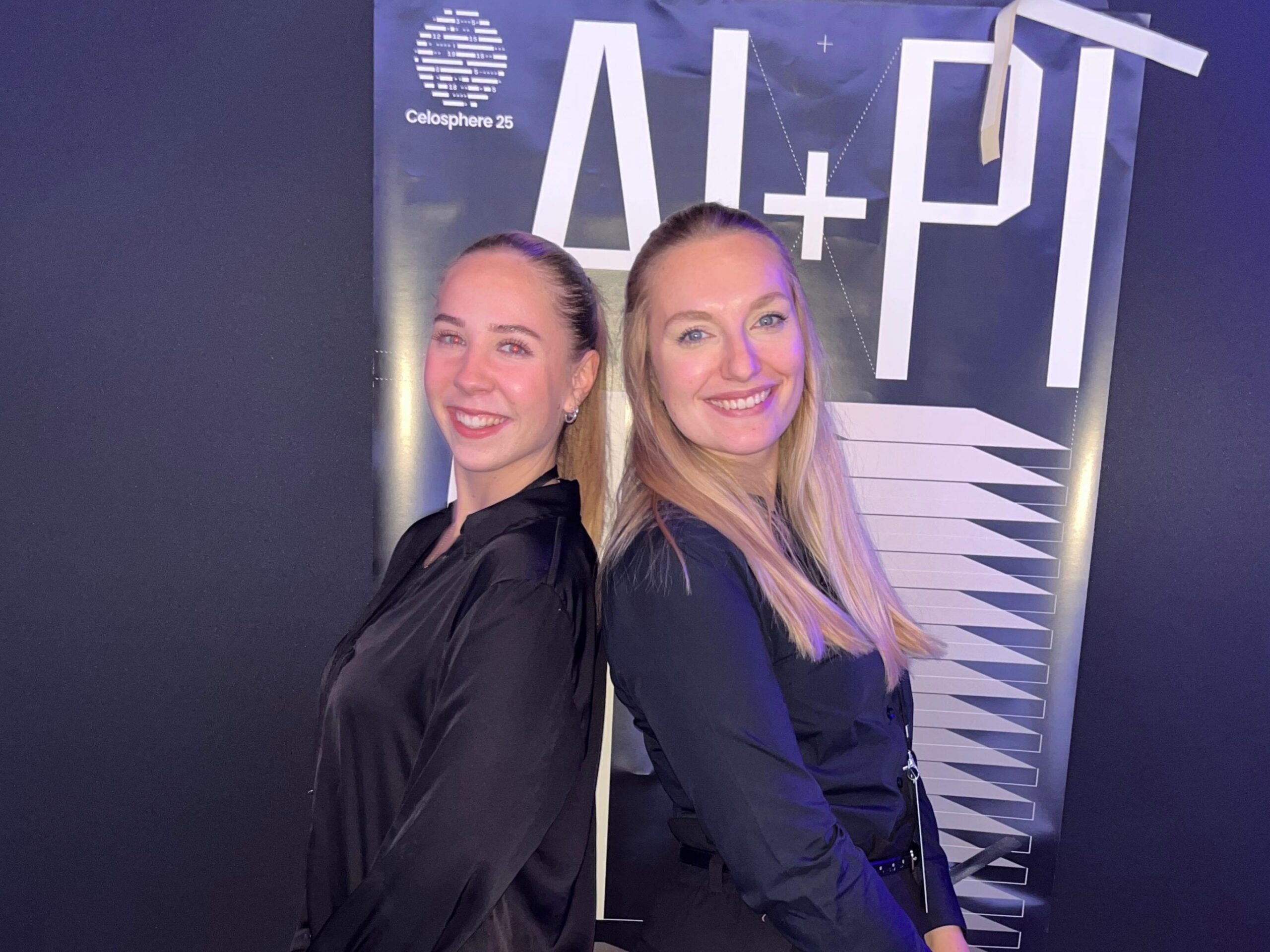 Zwei Hostessen in schwarzen Blusen stehen Rücken an Rücken vor einer Fotowand, eleganter Promotion- und Empfangsservice bei Event und Messe