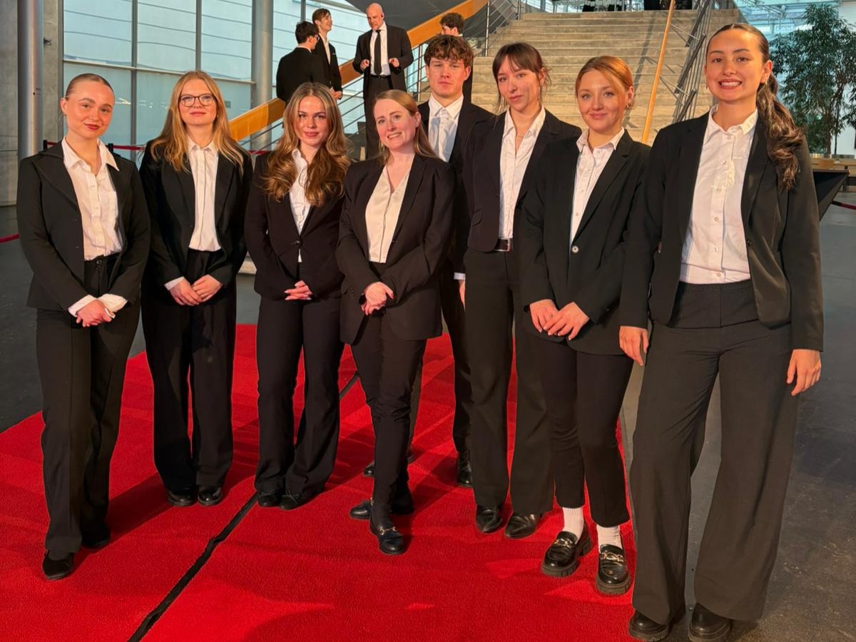 Hosts und Hostessen aus Berlin in Anzugshosen, Hemden und Blazern auf dem roten Teppich vor einer Treppe, lächelnder Empfang bei Gala und Event.