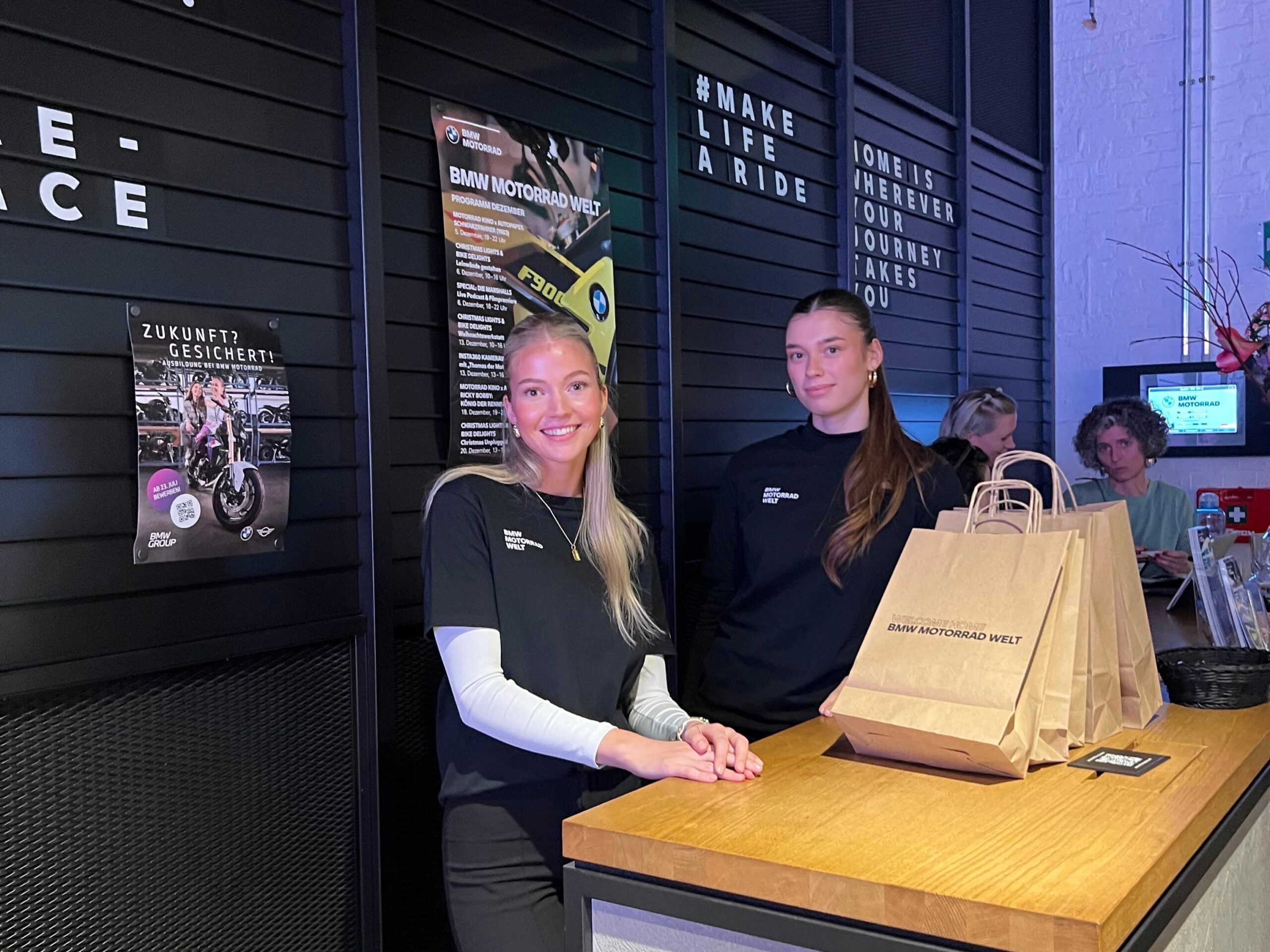 Zwei Aufbauhelferinnen in schwarzer Kleidung arbeiten hinter einem Tresen mit Goodies, professioneller Hands-Service bei Event und Promotion Einsatz