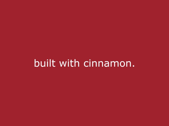 Roter Hintergrund mit beiger Schrift „Built with cinnamon“, modernes Statement für Auf- und Abbaupersonal, zuverlässigen Eventsupport und professionelle Umsetzung hinter den Kulissen