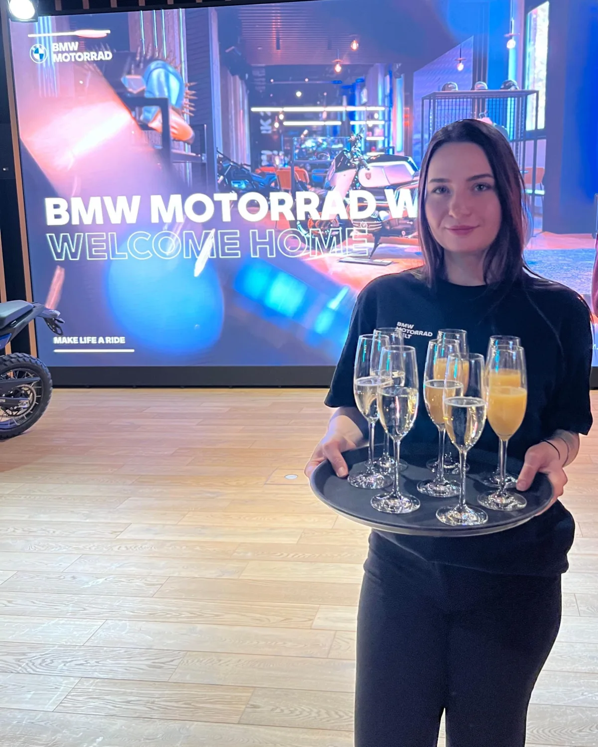 Servicekraft mit einem Tablett Sektgläser bei einem BMW-Motorrad-Event