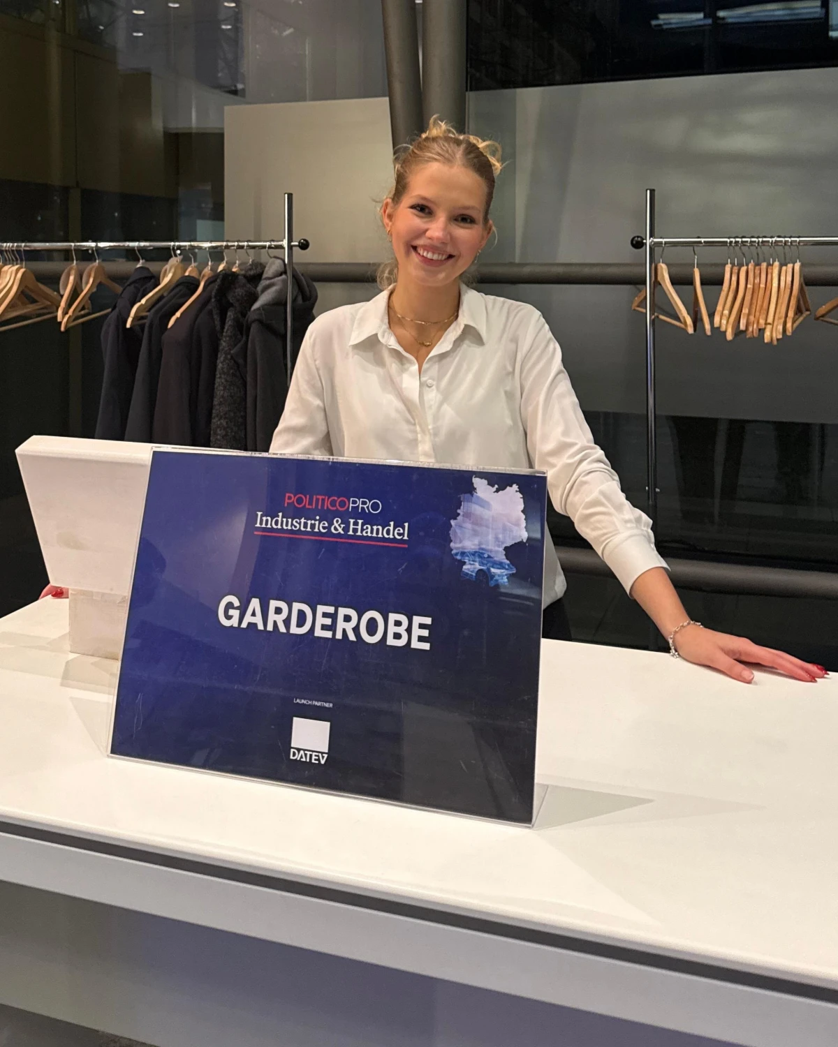 Hostess in weißer Bluse an der Garderobe einer Veranstaltung