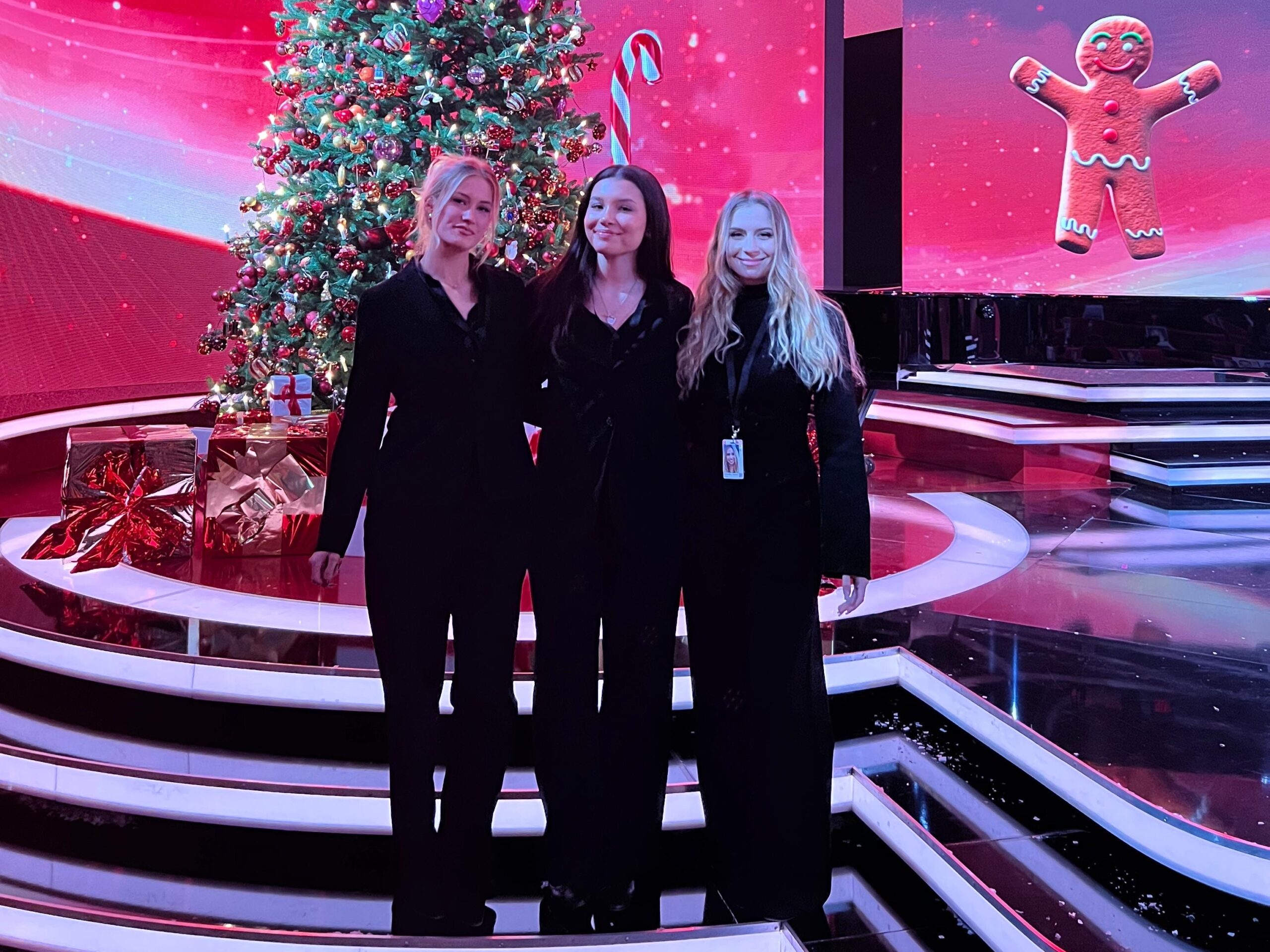 Drei Hosts und Hostessen in schwarzen Outfits vor einer weihnachtlich geschmückten Bühne mit Weihnachtsbaum, professioneller Eventservice von cinnamon in Mainz