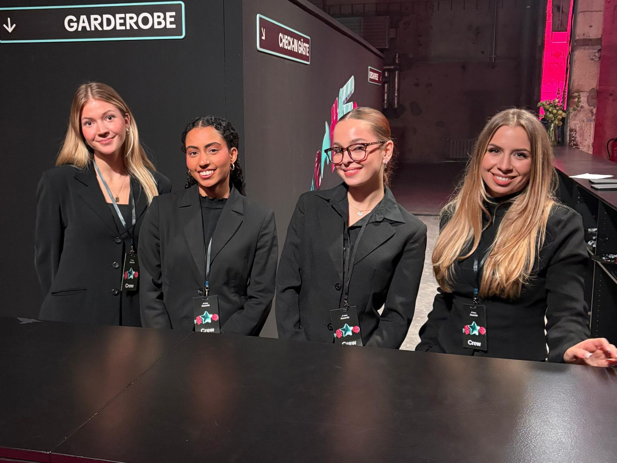 Vier Hostessen in schwarzen Anzügen bei einem TikTok Event, betreut durch cinnamon, lächelnder Promotion- und Empfangsservice mit Badges bei Messe und Markenpräsentation