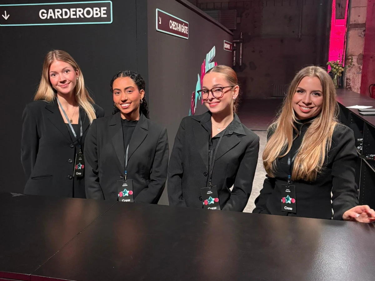 Vier Hostessen in schwarzen Anzügen bei einem TikTok Event, betreut durch cinnamon, lächelnder Promotion- und Empfangsservice mit Badges bei Messe und Markenpräsentation