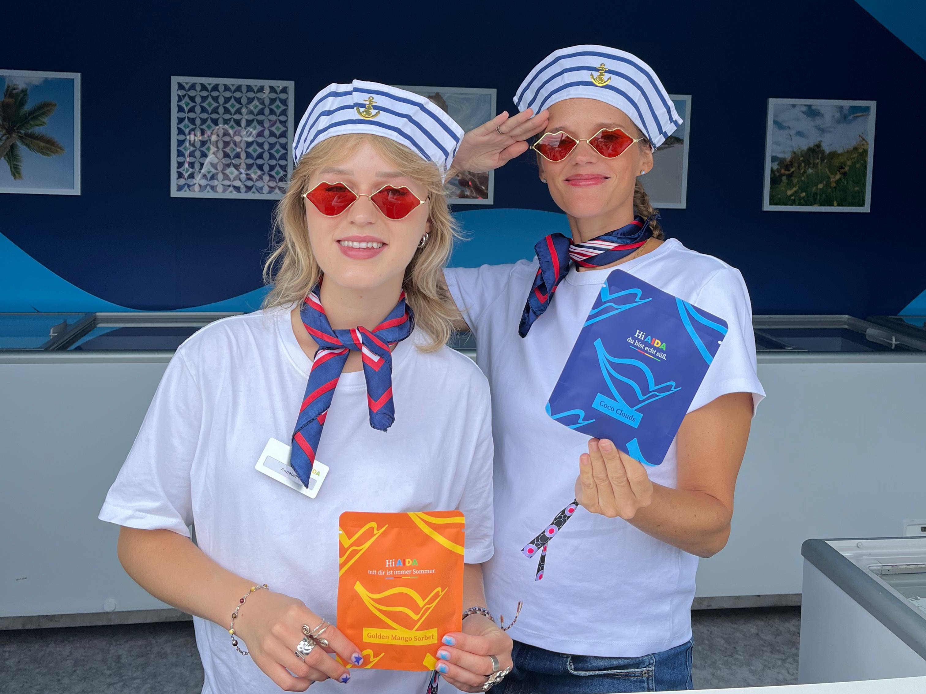 Zwei Promotion Hostessen im Matrosen-Outfit mit bunten Halstüchern halten Flyer in der Hand, lächelnder Einsatz bei Event, Messe und Markenpromotion