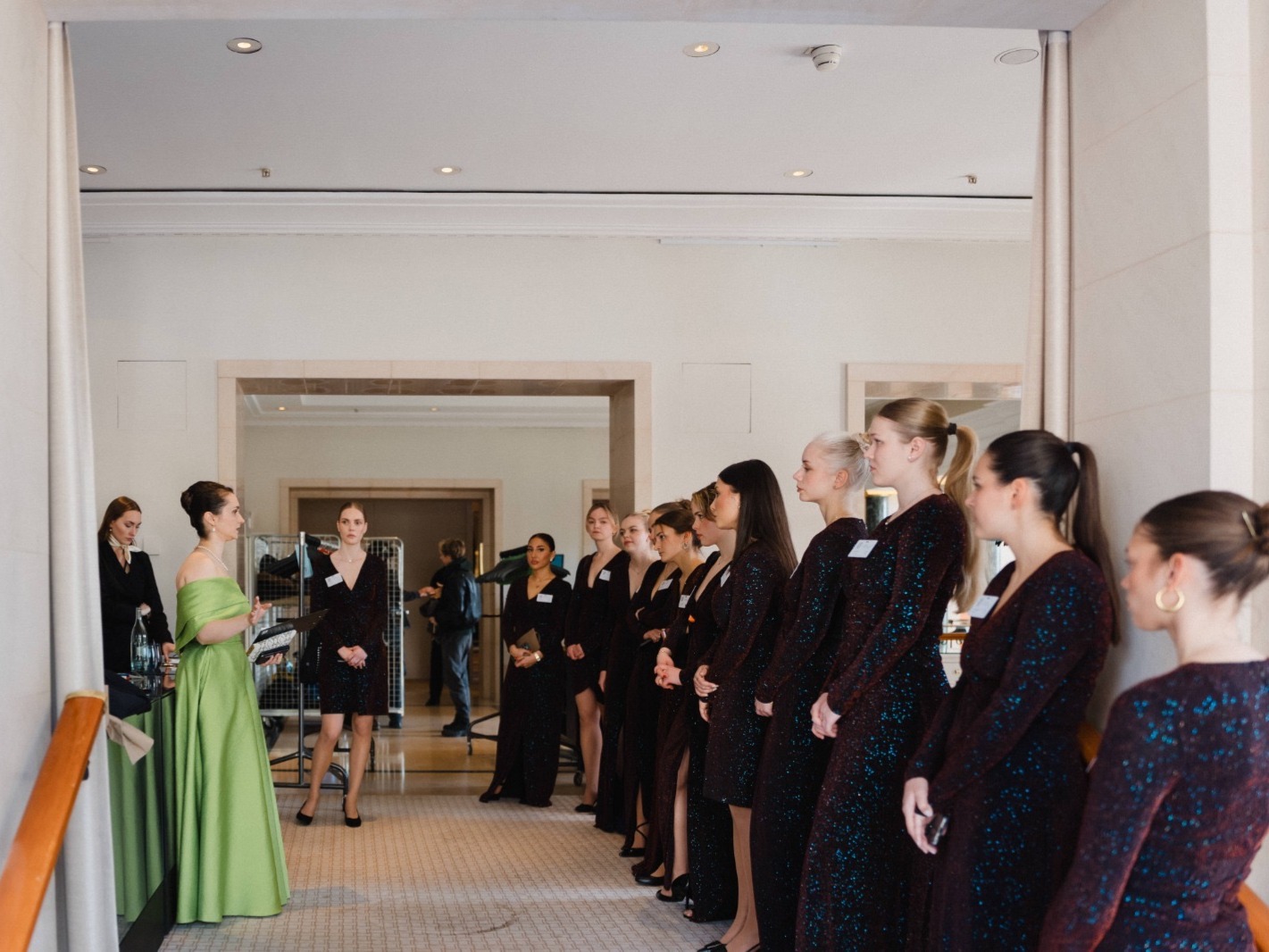 Frau im grünen Kleid gibt einer Hostess Feedback und Anweisungen, professionelle Abstimmung bei Event, Promotion und Teamorganisation