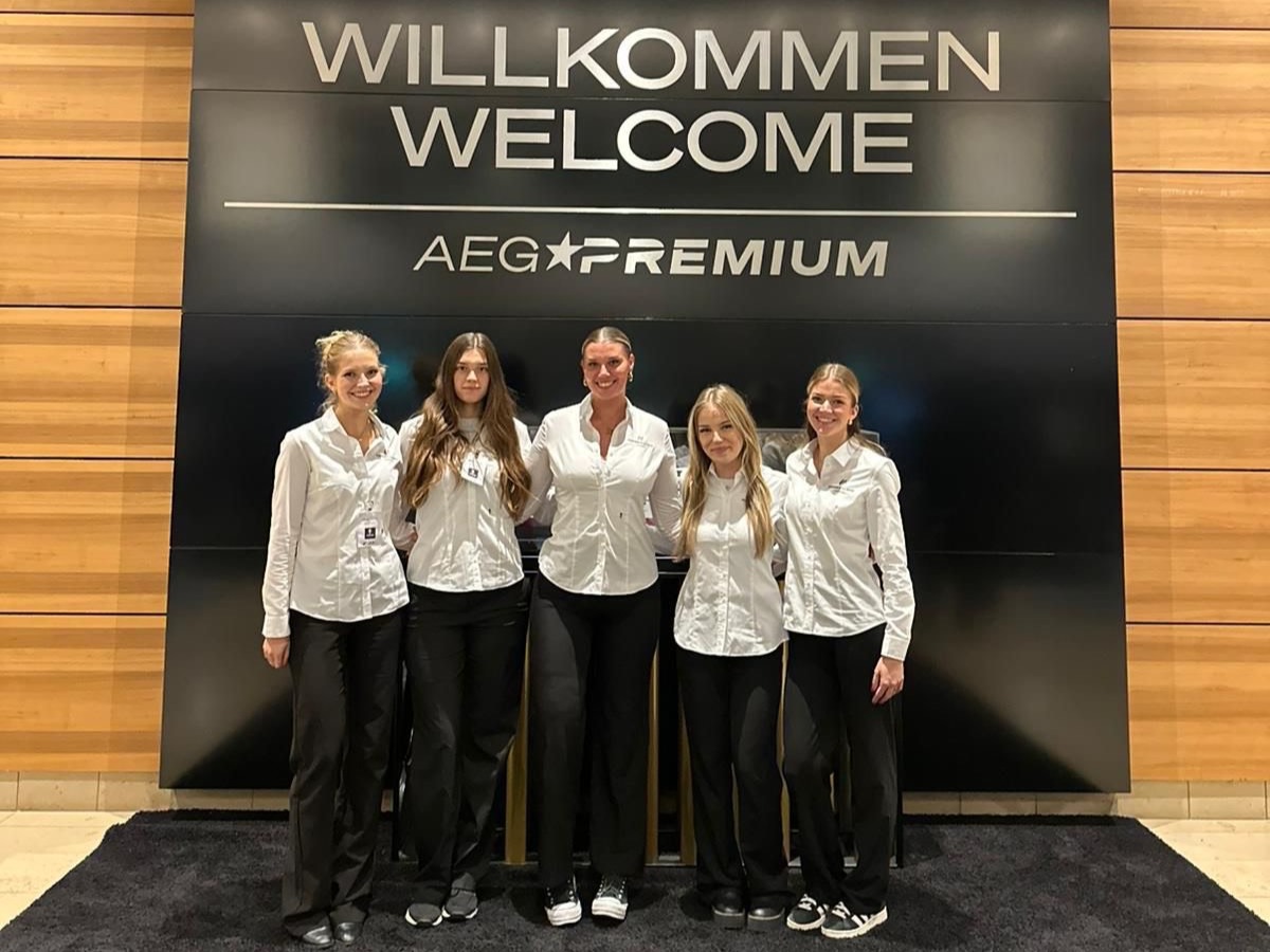 Fünf Hostessen in weißen Blusen und schwarzen Anzugshosen bei der Akkreditierung eines Events in Kassel, lächelnder Empfangsservice von cinnamon