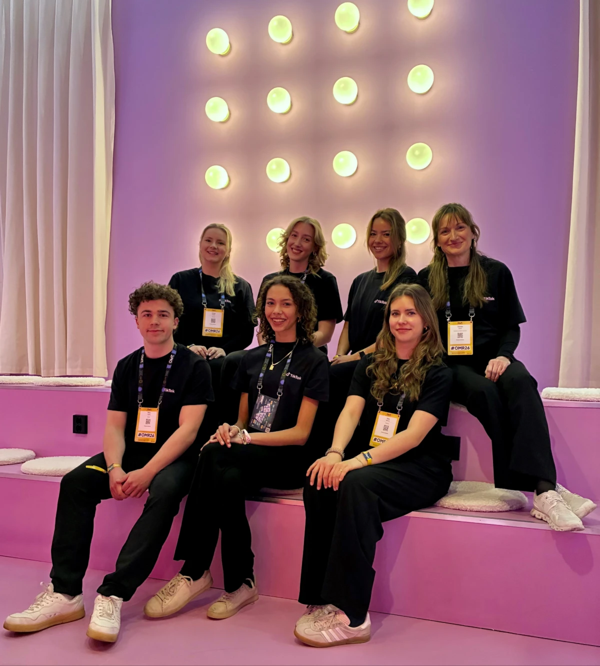 Team in schwarzen Outfits auf einer pinken Sitzstufe bei der OMR