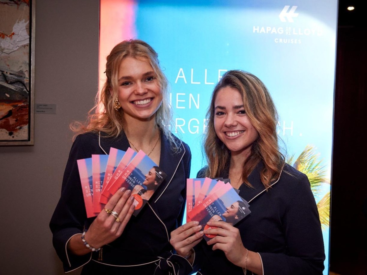 Zwei Hostessen lächeln mit Karten in der Hand in die Kamera, professioneller Hospitality- und Empfangsservice bei Event und Veranstaltung in Bremen