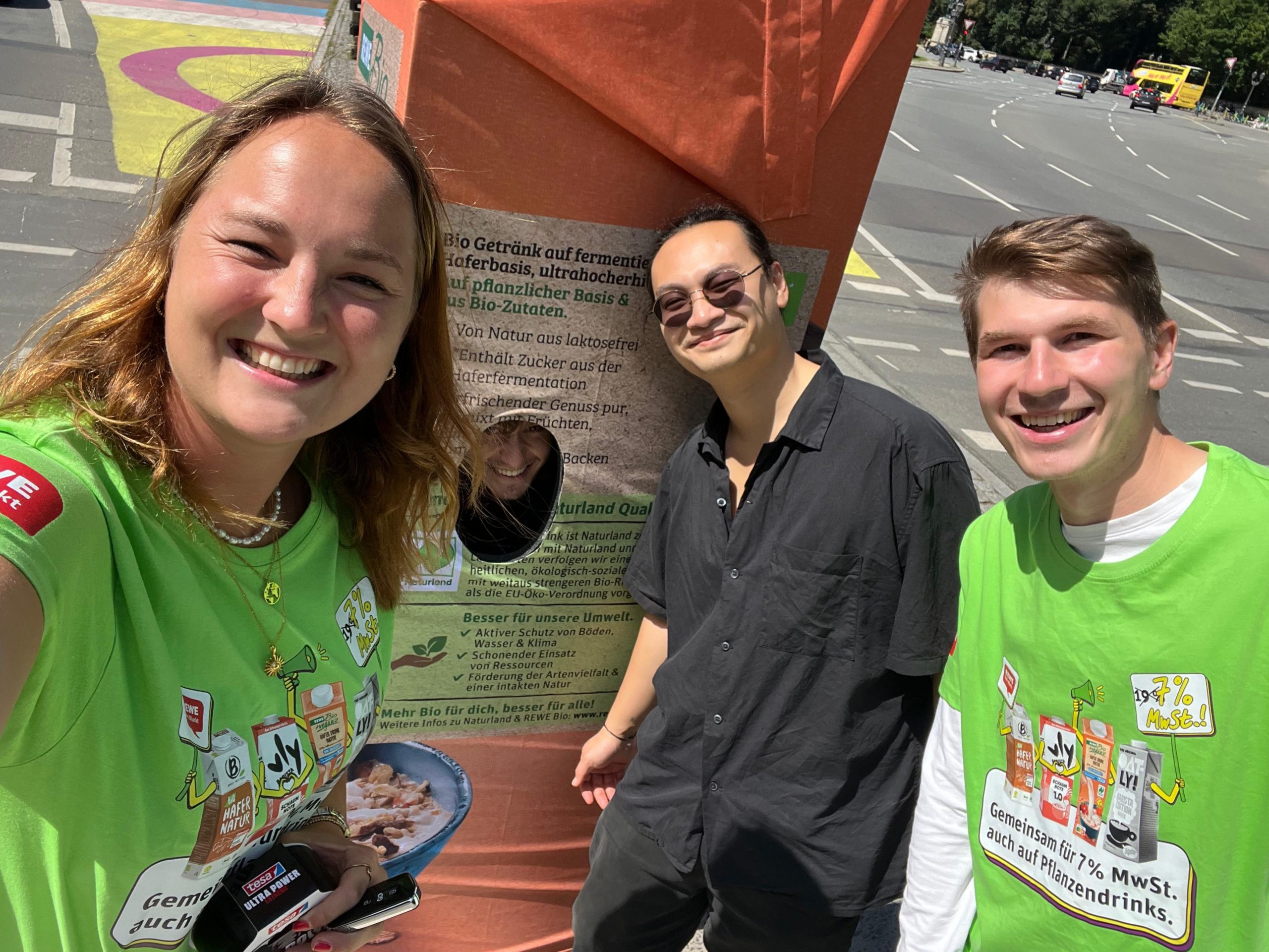 Drei Hosts und Hostessen bei einer REWE Promotion von cinnamon, zwei in grünen T-Shirts und einer im All-Black Look, lächelnder Markenauftritt bei Event und Sampling Aktion