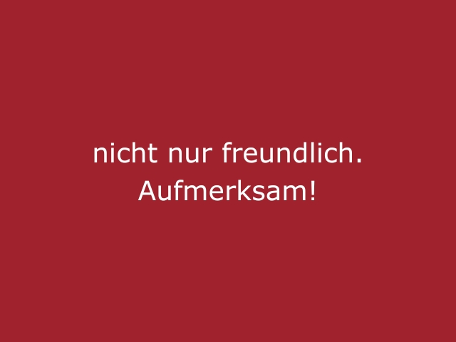 Roter Hintergrund mit beiger Schrift „Nicht nur freundlich, aufmerksam“, modernes Statement für Eventhostessen, Hospitality und die cinnamon Agentur