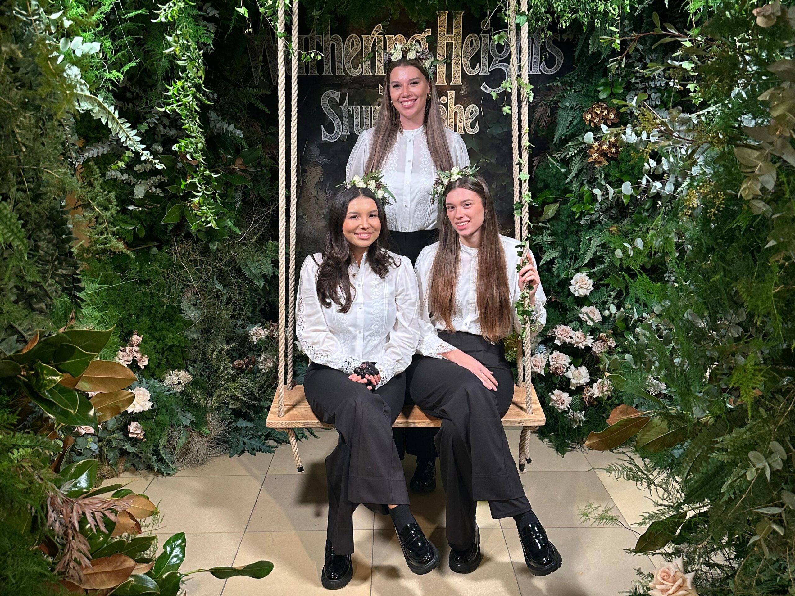 Hostessen bei der „Wuthering Heights“ Premiere in Berlin mit Blumenkränzen vor einer Blätter-Fotowand, stilvolle Eventinszenierung mit Holzschaukel und eleganter Gästebetreuung