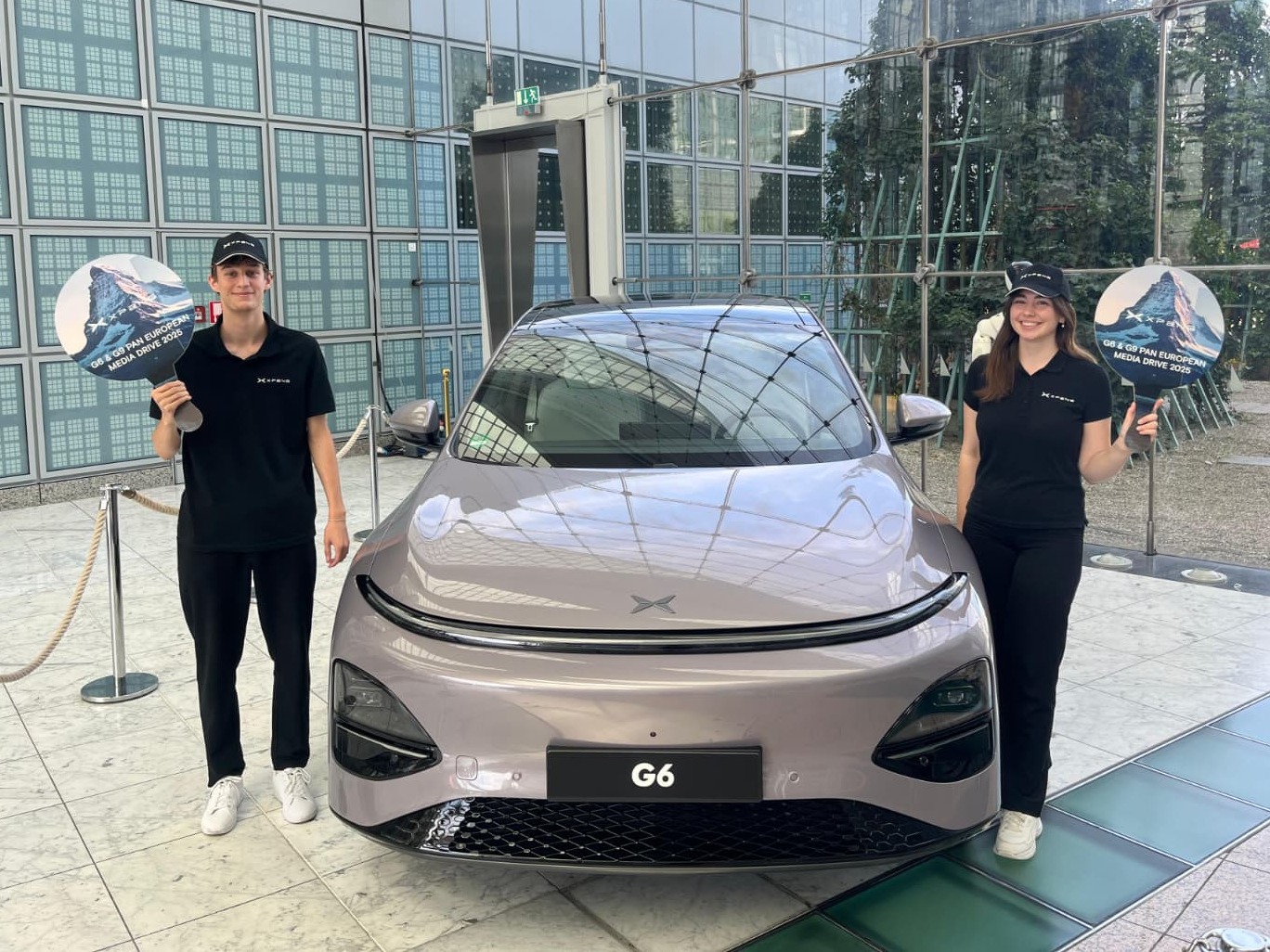 Zwei Hostessen bei einem XPENG Drive Test in Bremen stehen neben einem Fahrzeug in schwarzen Outfits, lächelnde Promotion bei Automotive Event und Markenpräsentation