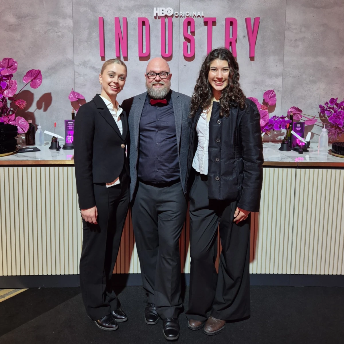 Zwei Hostessen und ein Gast vor einem „Industry“-Schriftzug am Empfang