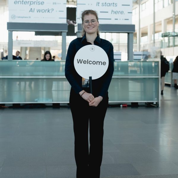 Transferhostess im schwarzen Outfit bereit zur Begrüßung von Gästen, freundlicher Empfangsservice bei Event, Messe und Veranstaltung