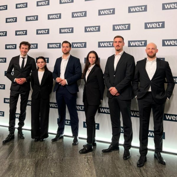 Hosts und Hostessen in schwarzen Anzügen mit weißen Hemden vor einer WELT Fotowand, eleganter Empfangsservice und professionelle Eventbetreuung bei Gala und Medienveranstaltung