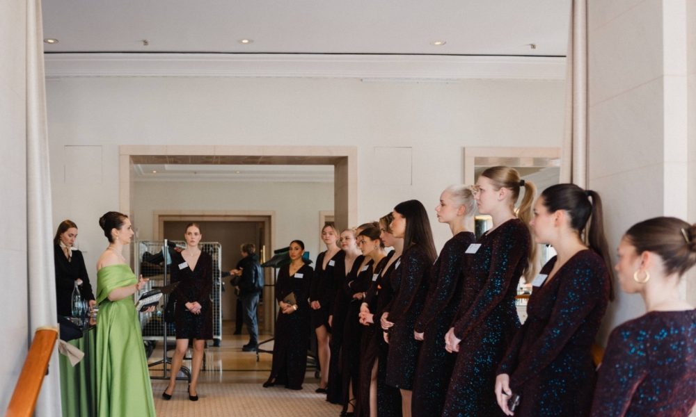 Frau im grünen Kleid gibt einer Hostess Feedback und Anweisungen, professionelle Abstimmung bei Event, Promotion und Teamorganisation